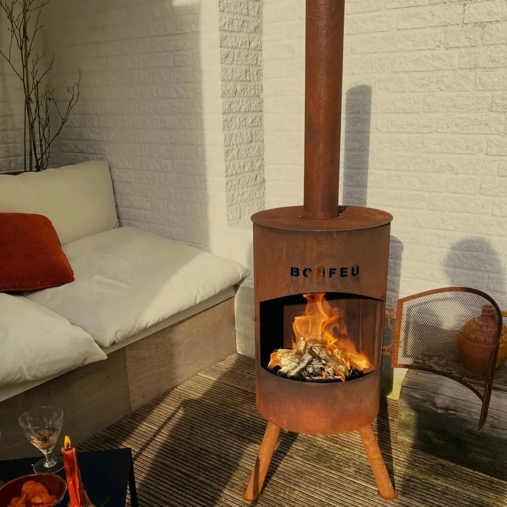 Rust-colored corten steel bonfeu bonton large outdoor fireplace with tall chimney and three legs visible from front