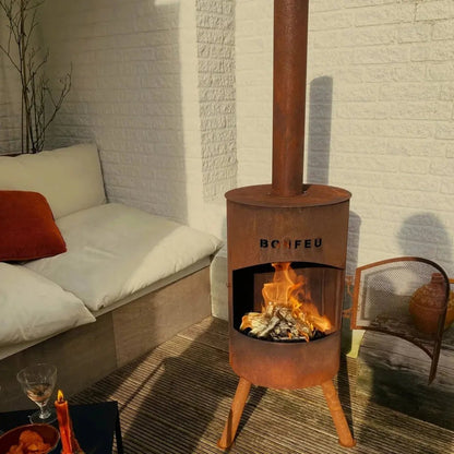 Rust-colored corten steel bonfeu bonton large outdoor fireplace with tall chimney and three legs visible from front