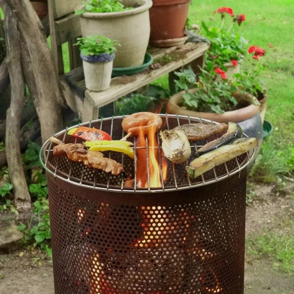 Rusty metal bonfeu bonves 34 fire pit fire basket charcoal grill with perforated sides and skewered vegetables over embers