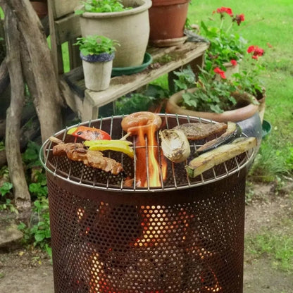 Rusty metal bonfeu bonves 34 fire pit fire basket charcoal grill with perforated sides and skewered vegetables over embers