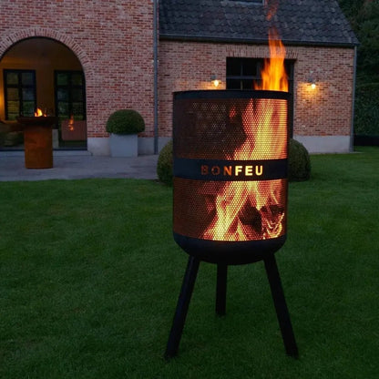 Black metal bonfeu bonves 45 fire pit with perforated cylindrical body and tripod legs glowing with warm flames