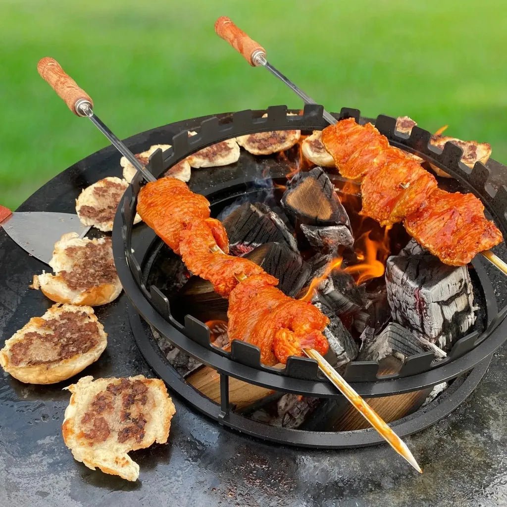 Black cast iron charcoal grill with wooden handled bonfeu skewers grilling seasoned meat over glowing coals