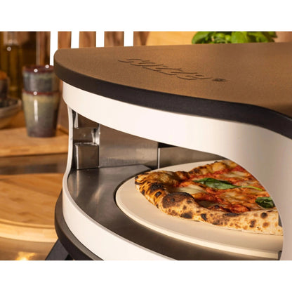 A cozze 17 inch gas pizza oven with rotating stone features a matte brown top and white body with a fresh pizza