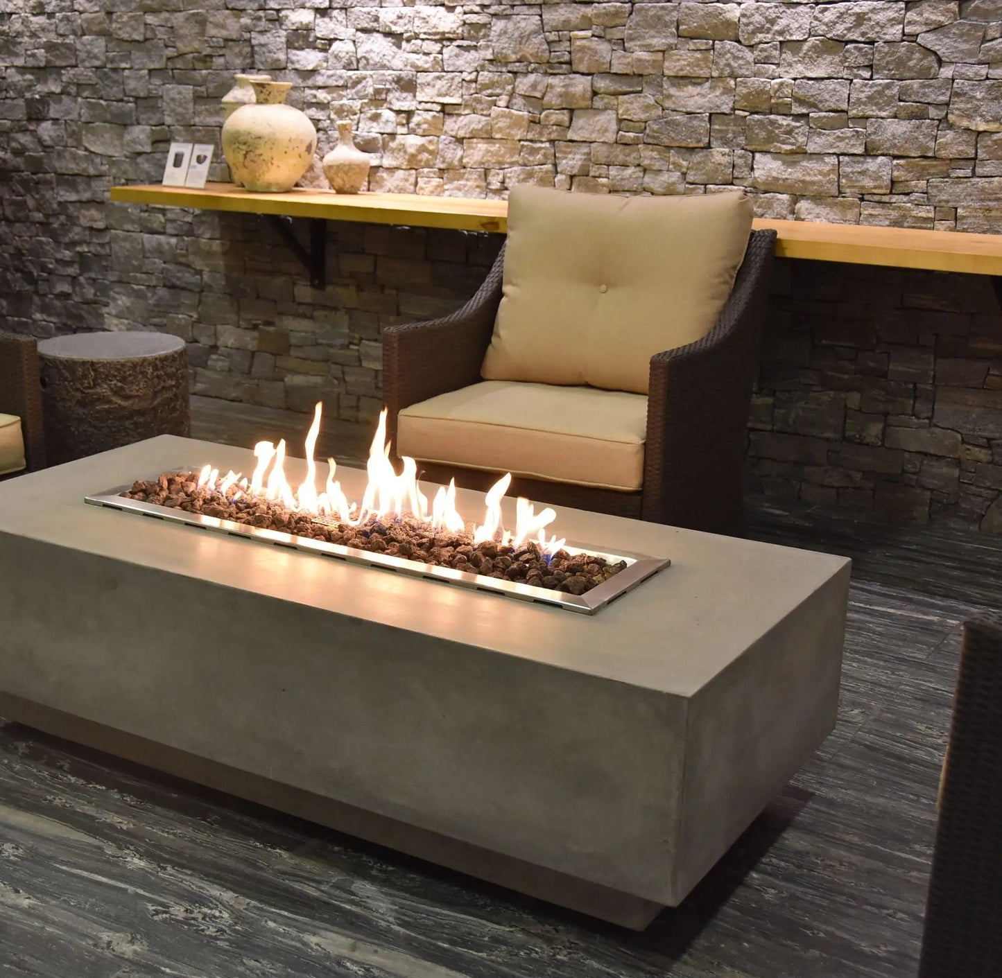 Elementi Granville fire table in concrete with a rectangular metal frame holding glowing embers and flickering flames