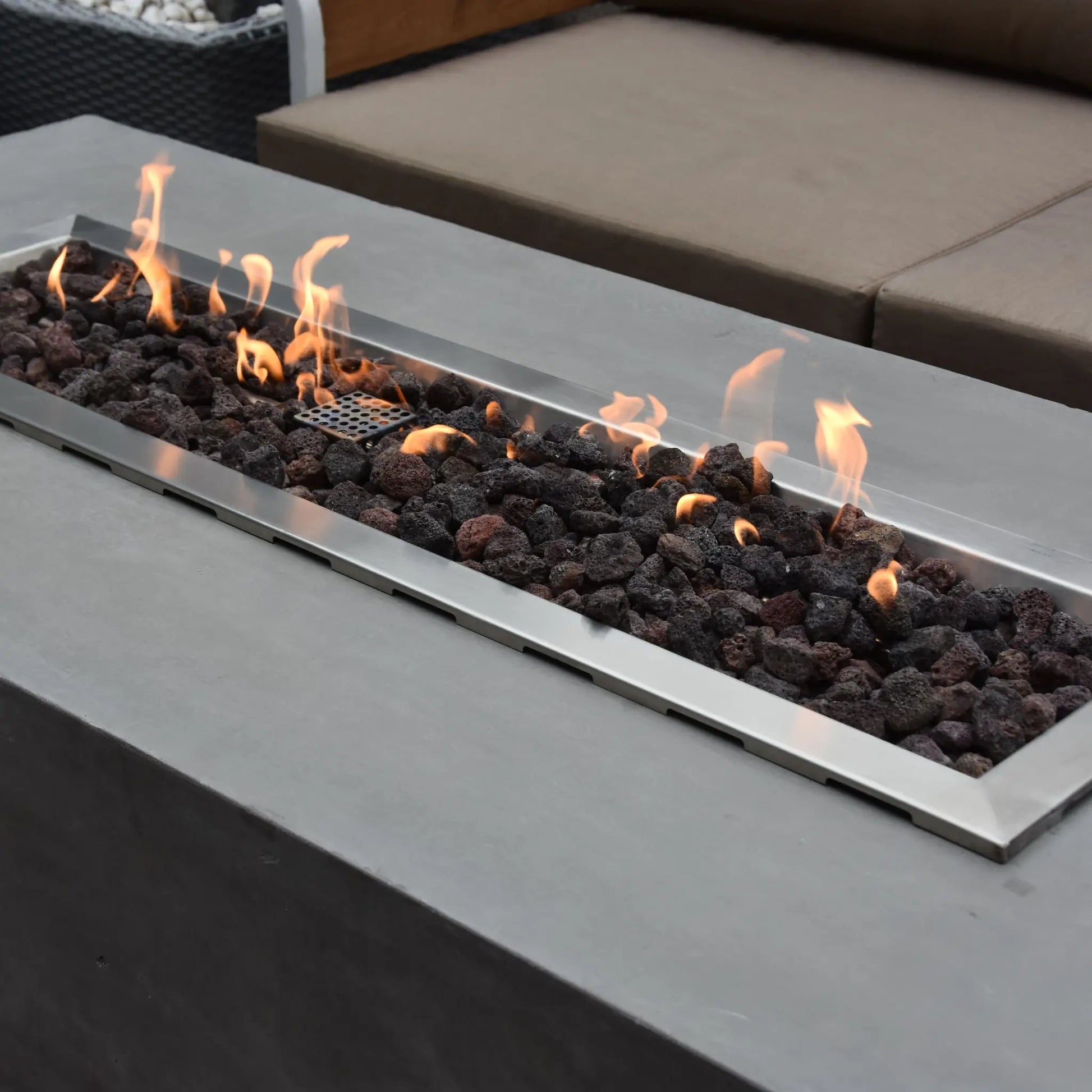 Elementi Granville fire table stainless steel fire pit with black lava rocks and flickering orange flames