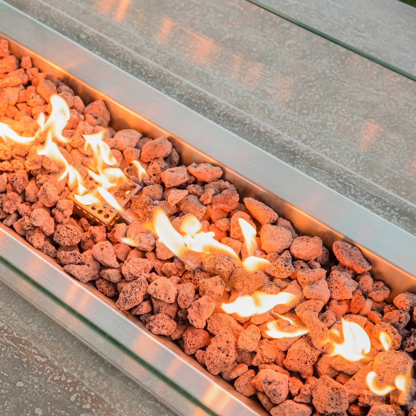 Elementi hampton fire table rectangular stainless steel fire pit with orange lava rocks and glowing flames 13.2 kw