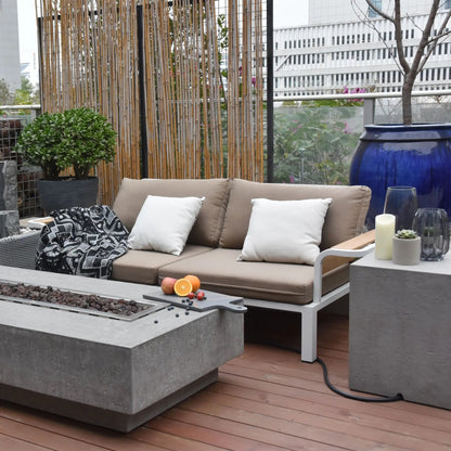 Beige outdoor sofa with white pillows and black and white throw blanket paired with elementi hampton fire table 13.2 kw