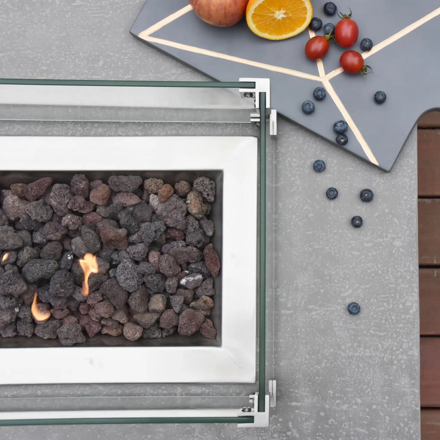 Elementi Hampton fire table 13.2 kW rectangular outdoor fire pit with white metal frame glass sides and dark volcanic rock fill