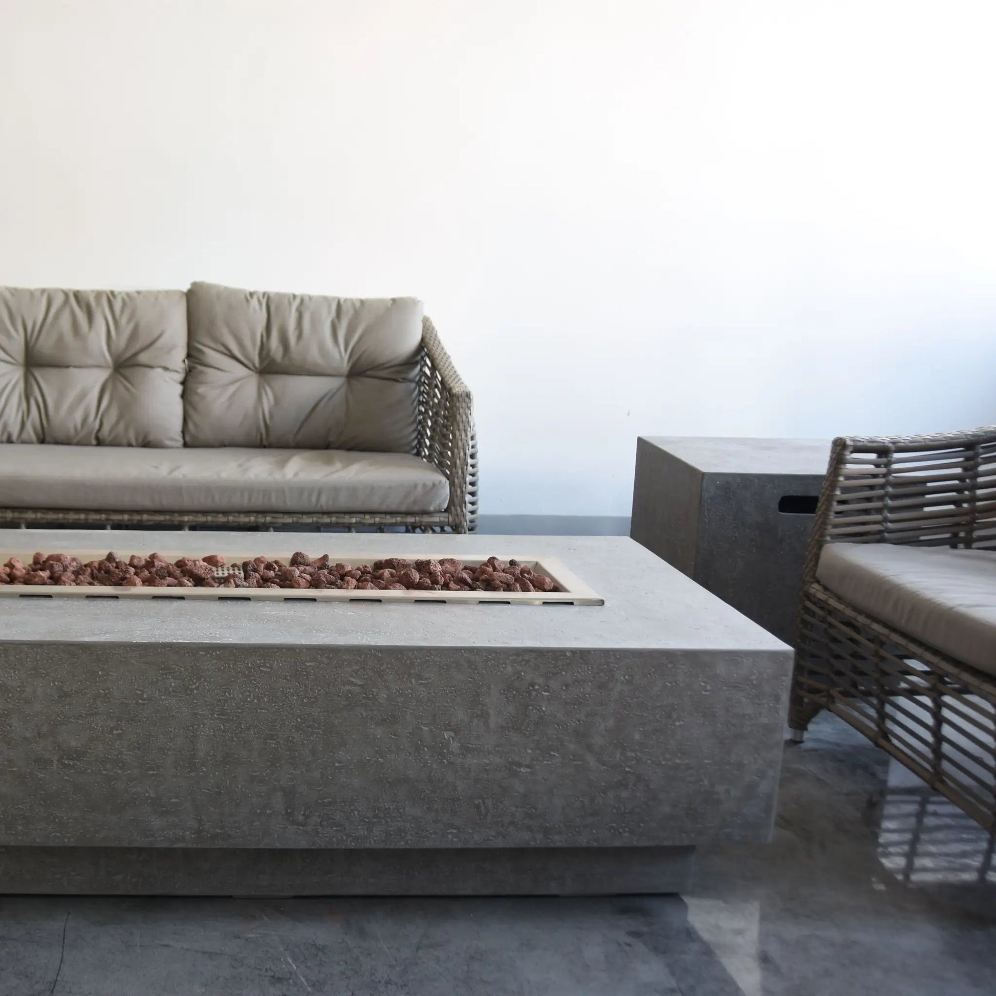 Elementi Kingsale gray concrete fire table with 13.2 kW output and rectangular opening filled with reddish-brown fuel beads