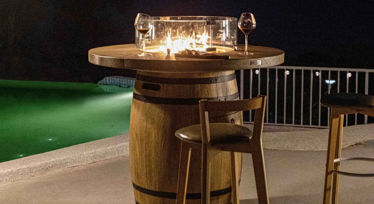 Wooden barrel table with glass fire pit and two wine glasses on top in elementi lafite barrel bar fire table 13.2 kw