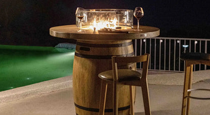 Wooden barrel table with glass fire pit and two wine glasses on top in elementi lafite barrel bar fire table 13.2 kw