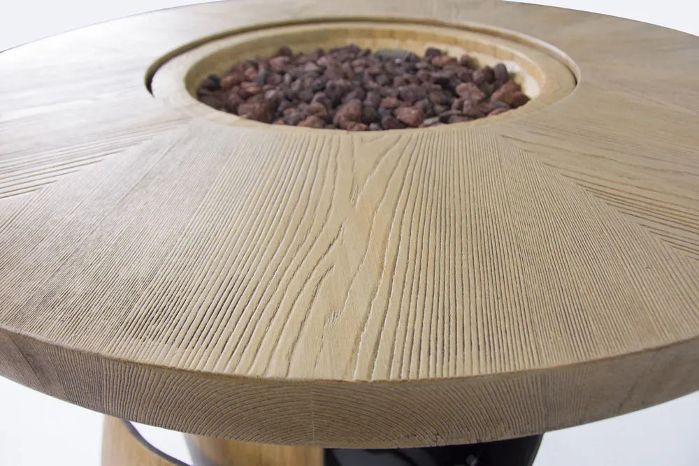 Elementi Lafite Barrel Bar fire table with light-colored wooden frame and circular dark brown gravel fire pit inset
