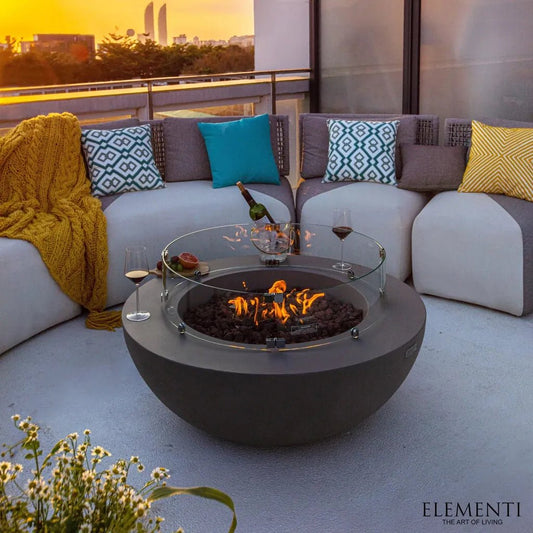 Gray spherical fire pit Elementi Lunar Bowl Fire Table with glass top and burning flames for outdoor warmth