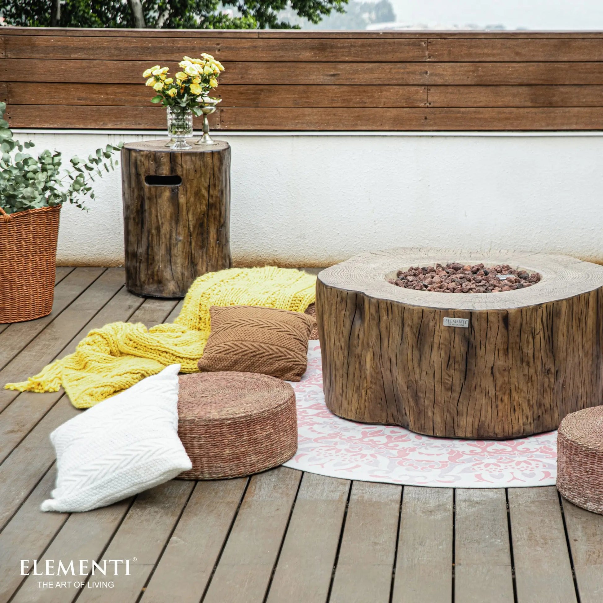 Rustic wooden Elementi Manchester fire table with natural bark finish and dark brown lava rocks for outdoor heating
