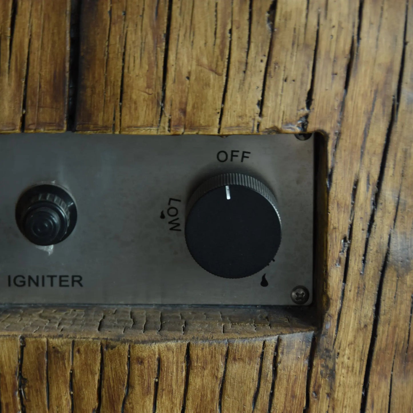 Metal control panel with black rotary knob and ignition switch set into rustic wood for elementi manchester fire table 13.2 kw