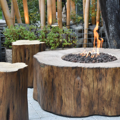 Elementi Manchester fire table featuring rustic wooden fire pit from single tree trunk with charred edges and glowing flames
