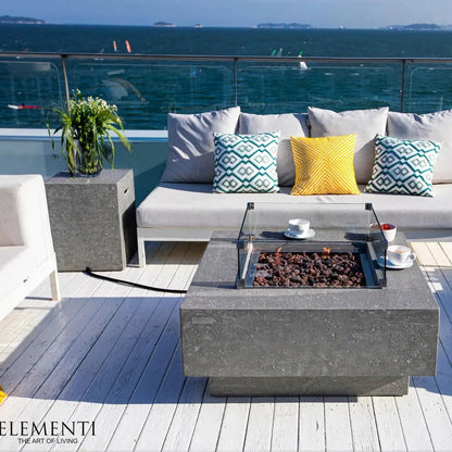Modern gray concrete Elementi Manhattan gas fire table with glass top and visible flame for outdoor use