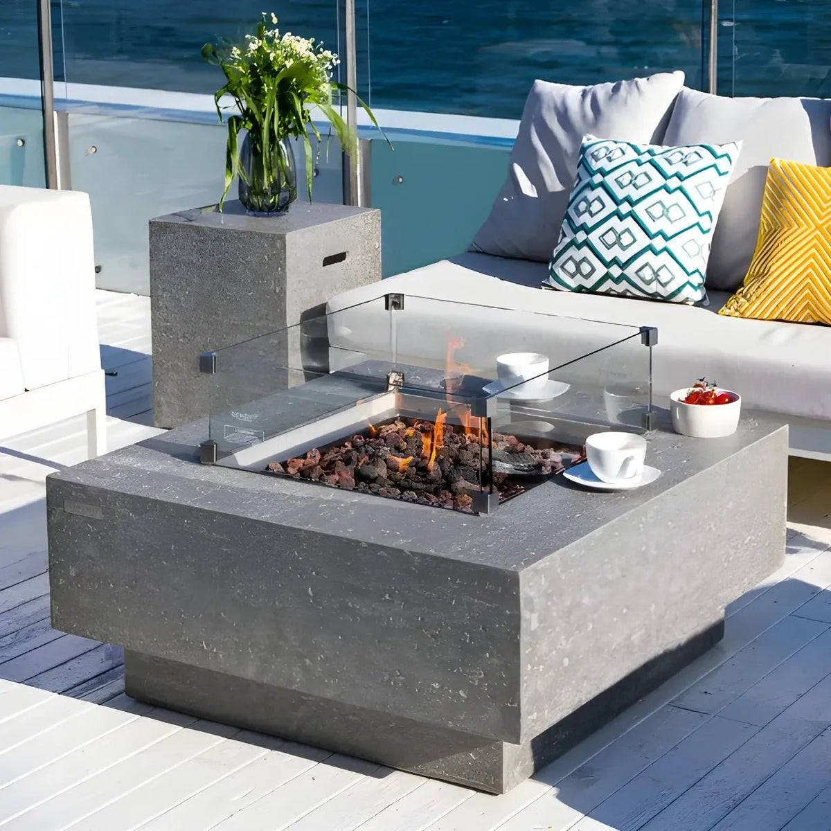 Elementi Manhattan gas fire table in light grey concrete with glass enclosure and burning coals on top