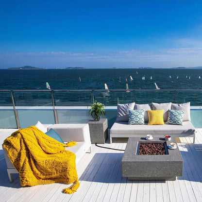 Vibrant yellow knitted throw blanket draped over white outdoor sofa beside elementi manhattan gas fire table light grey