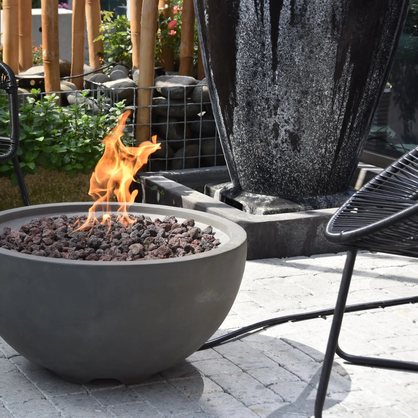 Gray concrete Elementi Modeno Nantucket fire bowl with glowing orange flames over dark volcanic rocks 11.7 kW
