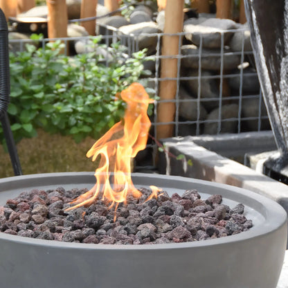 Elementi Modeno Nantucket gray fire pit filled with dark volcanic rocks and a lively orange flame 11.7 kW OFG116