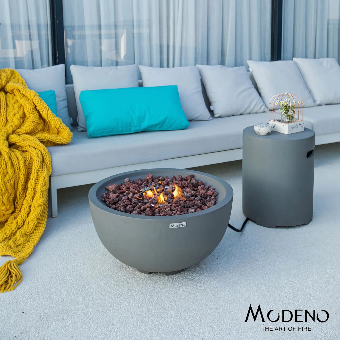 Elementi Modeno Nantucket fire bowl 11.7 kW gray concrete with glowing orange flames and reddish brown stones inside