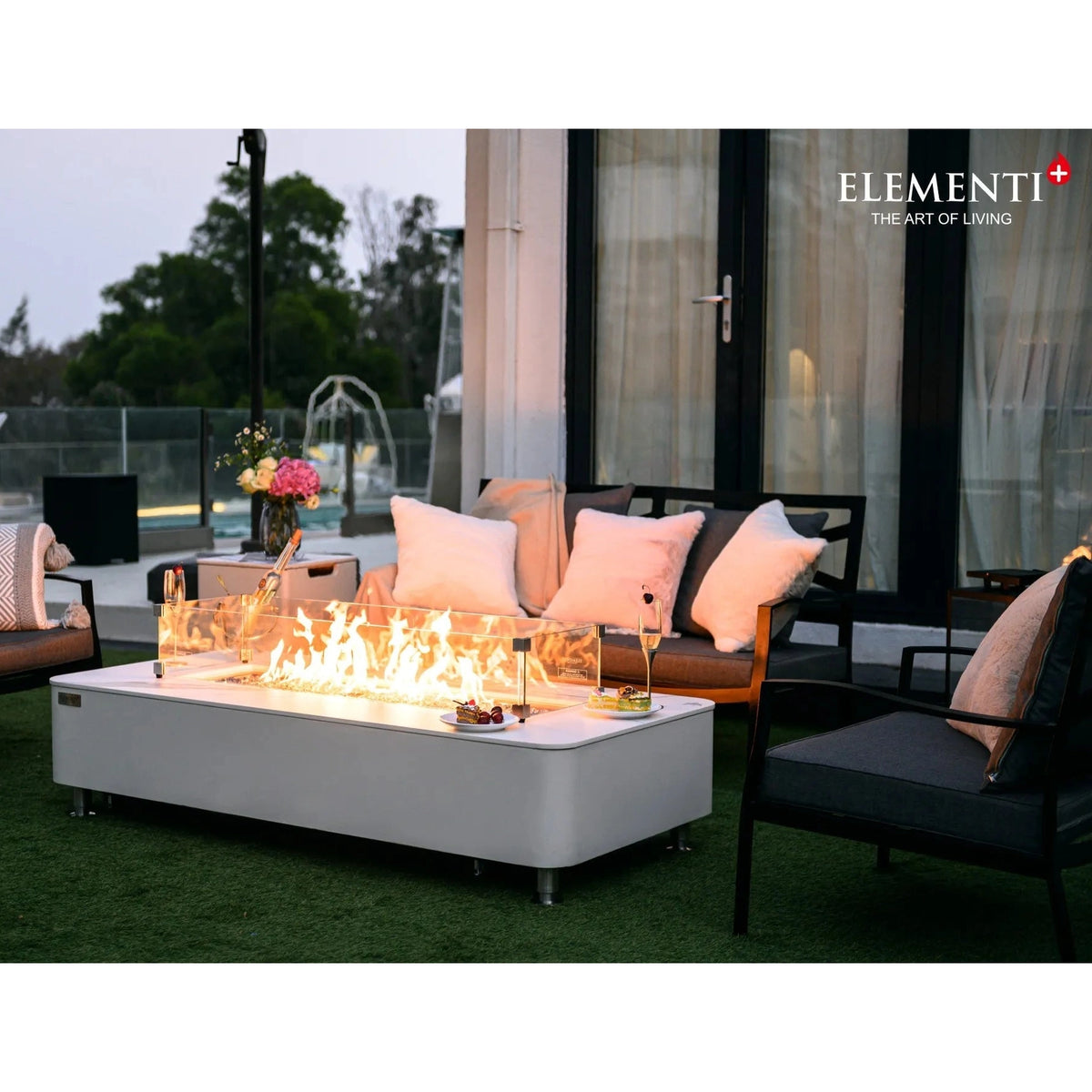 White rectangular Elementi Plus Athens fire pit table with glass enclosure and glowing flames 16 kW OFP102BW