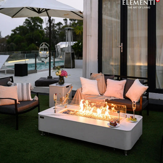 White rectangular fire pit table elementi plus athens with glass enclosure and glowing flames inside 16 kW
