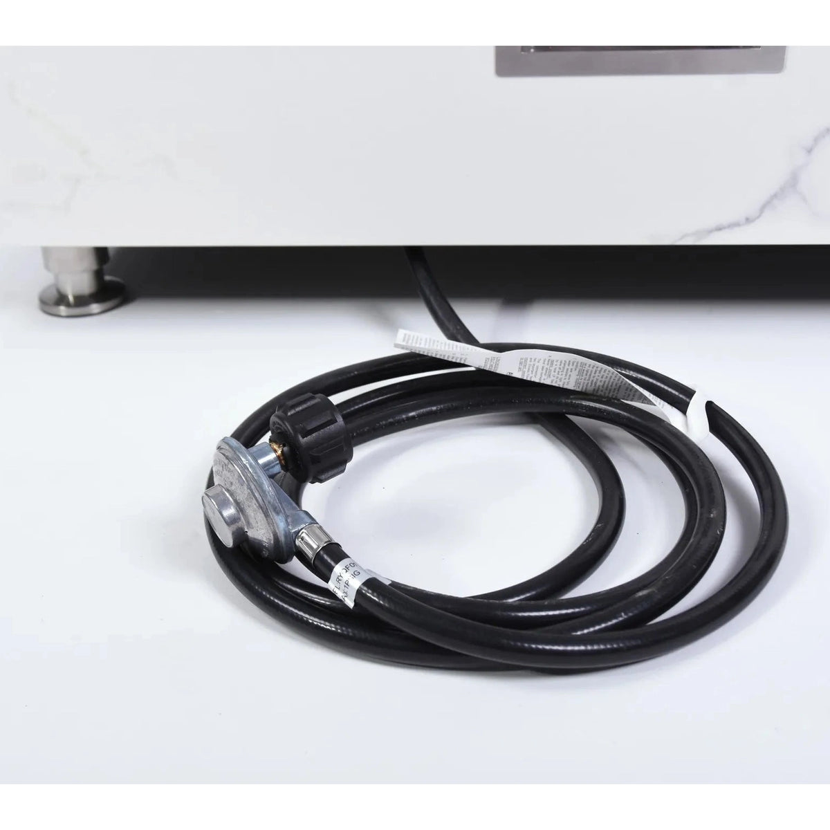 Black gas hose with metallic regulator and black plastic fittings coiled neatly for elementi plus bianco fire table 16 kw