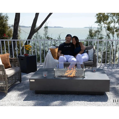 Modern gray rectangular Elementi Plus Cannes fire table with glass enclosure and visible flames 16 kW OFG416DG