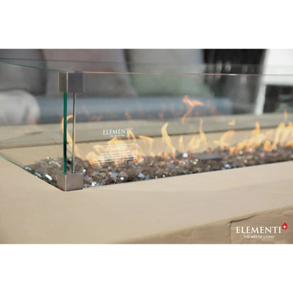 Elementi Plus Colorado fire table with modern glass enclosure, sleek metallic frame, and glowing orange flames over gray pebbles