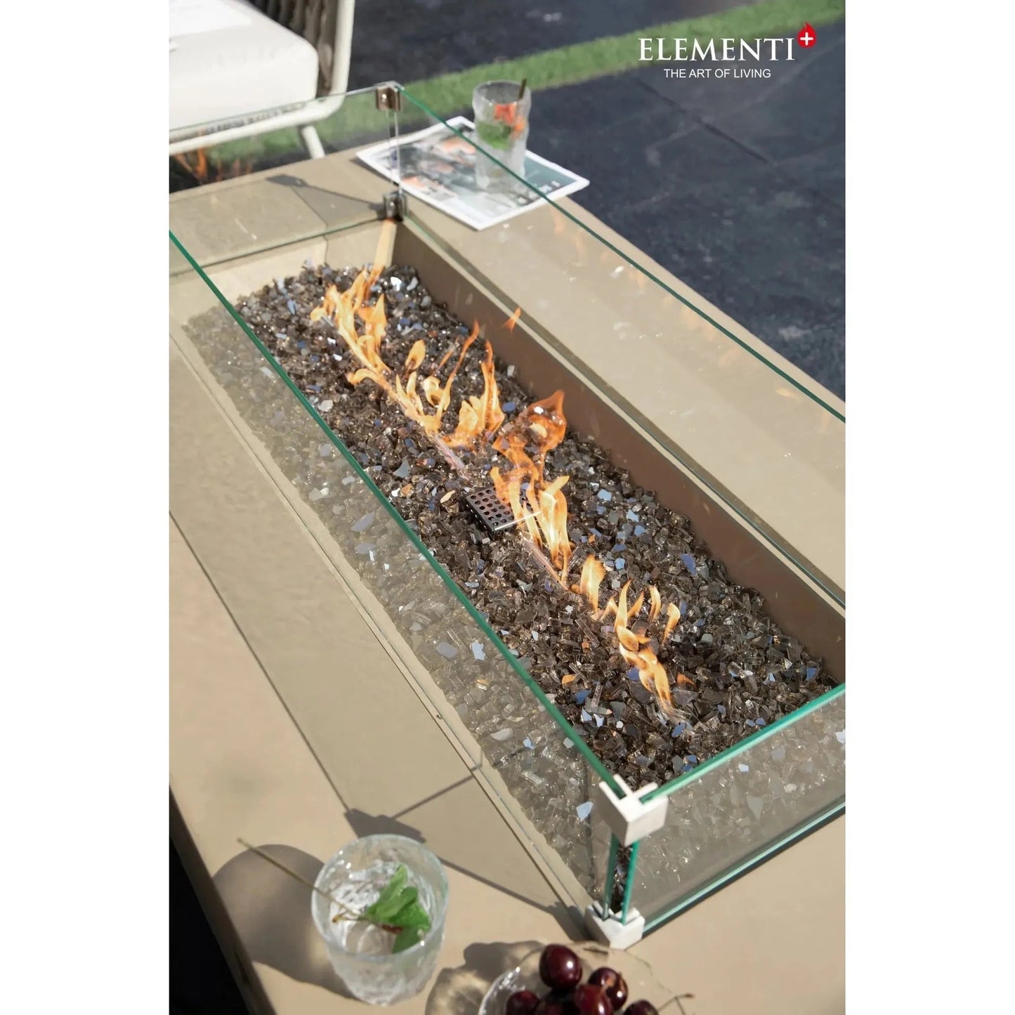 Elementi plus colorado fire table with glass enclosure and flickering flames over dark reflective mosaic stones