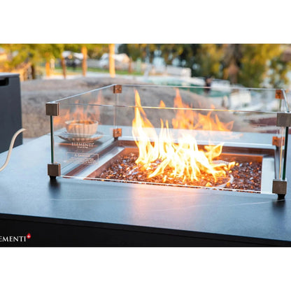 Elementi Plus Copenhagen porcelain top fire table with glass enclosure metallic frame and glowing orange flames over pebbles