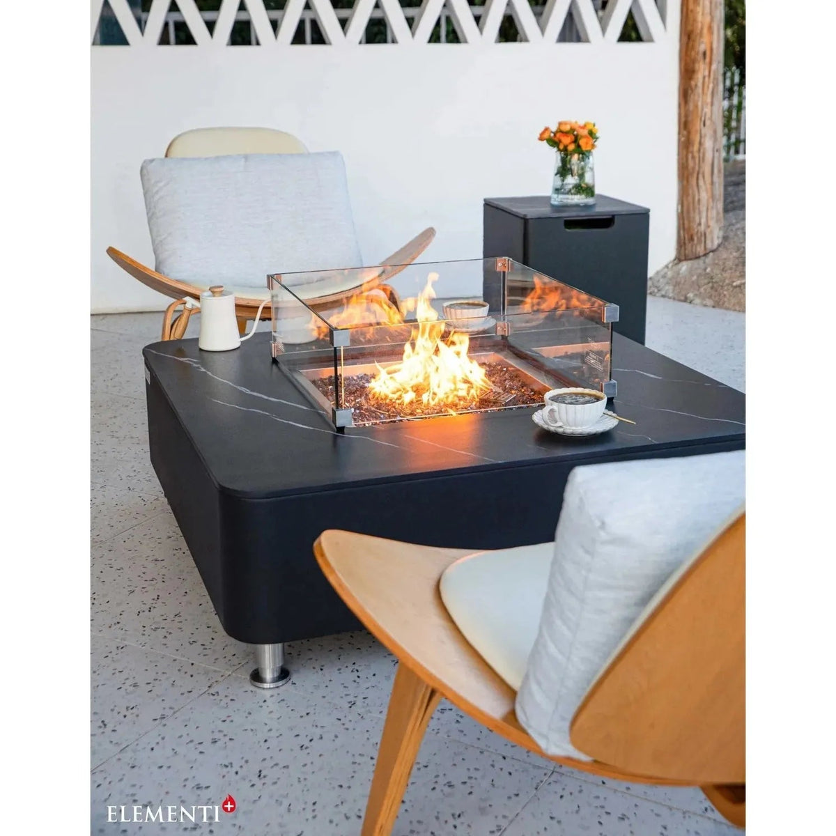 Black marble-top Elementi Plus Copenhagen porcelain fire table with glass enclosure and metal legs for outdoor use