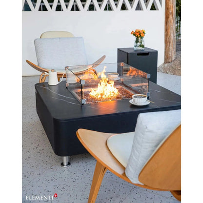 Black marble-top Elementi Plus Copenhagen porcelain fire table with glass enclosure and metal legs for outdoor use