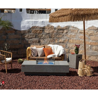 Modern gray concrete Elementi Plus Monte Carlo fire table with blue stones and active flame glass insert 16 kW
