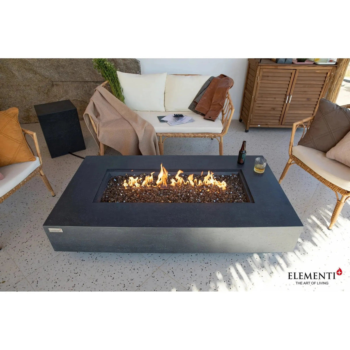 Elementi Plus Positano fire table with modern rectangular design dark gray concrete finish and glowing orange flames over black glass beads