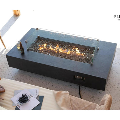 Black rectangular Elementi Plus Positano fire table with glass enclosure and glowing flames over dark pebbles