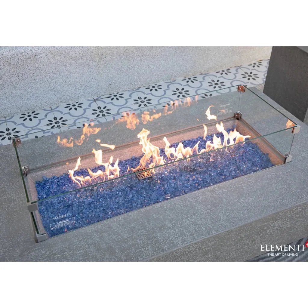 Elementi Plus Riviera glass fire table with blue decorative gravel and transparent sides for a modern outdoor ambiance