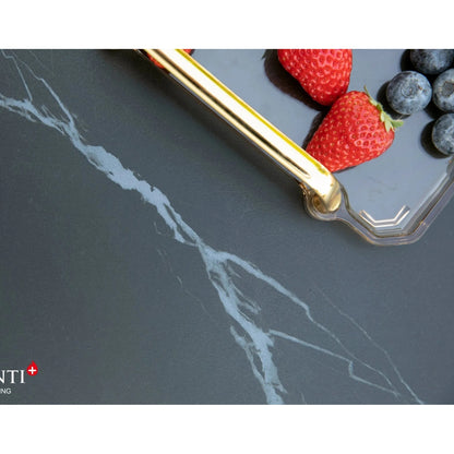 Gold-toned serving tongs resting on dark gray marble surface with white veining beside elementi plus sofia fire table 16 kW