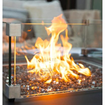 Elementi Plus Sofia fire table with a glass enclosure and metallic frame featuring vibrant orange flames on pebbles