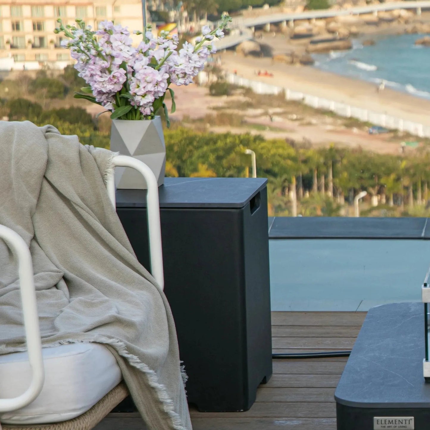 Elementi plus tank cover in black porcelain shown with a geometric gray ceramic vase holding light purple flowers