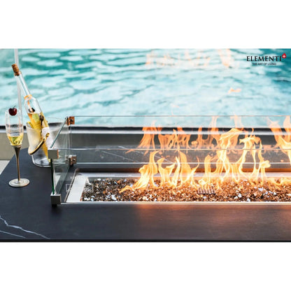 Modern glass-enclosed elementi plus valencia fire table with glowing orange flames over dark gray pebbles 16 kW
