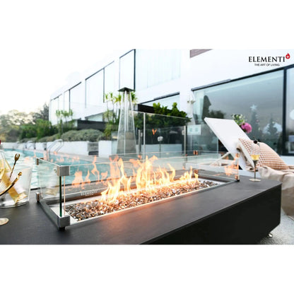Modern black rectangular elementi plus valencia fire table with glass enclosure and burning flames over decorative stones