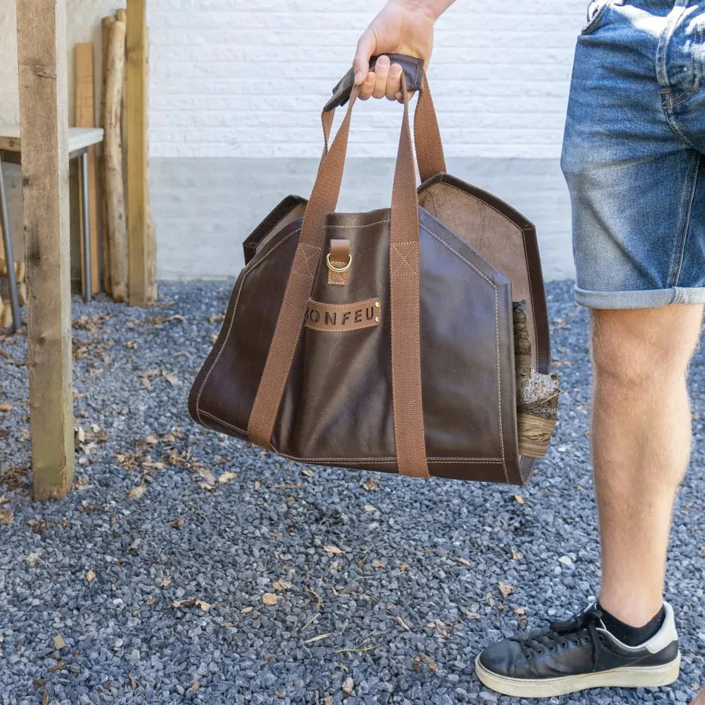 Brown leather bonfeu log bag with sturdy webbing straps and gold-tone metal buckle for carrying firewood