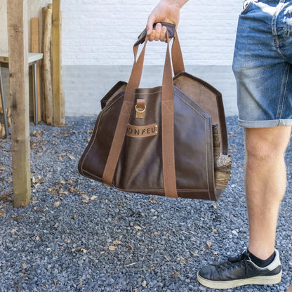 Brown leather bonfeu log bag with sturdy webbing straps and gold-tone metal buckle for carrying firewood