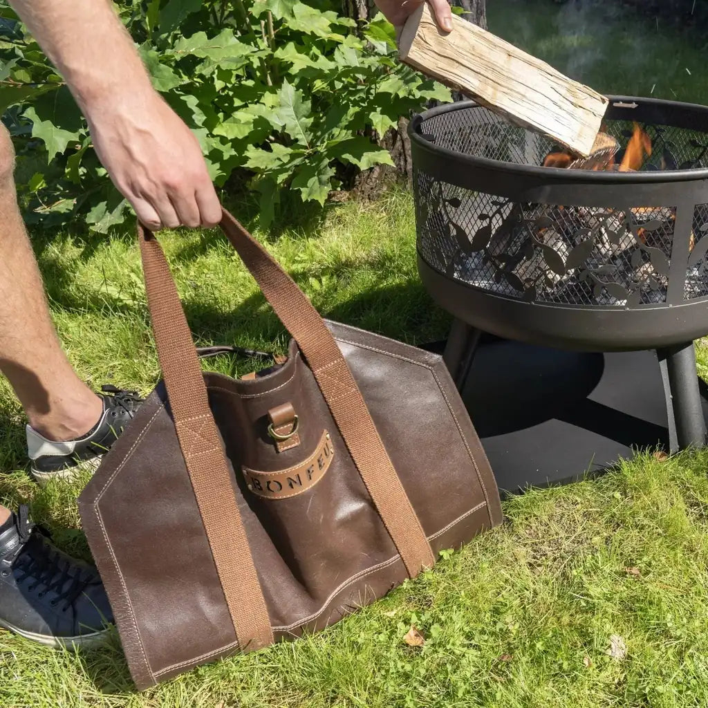 Brown leather bonfeu log bag with tan canvas straps and brass metal clasp for carrying firewood