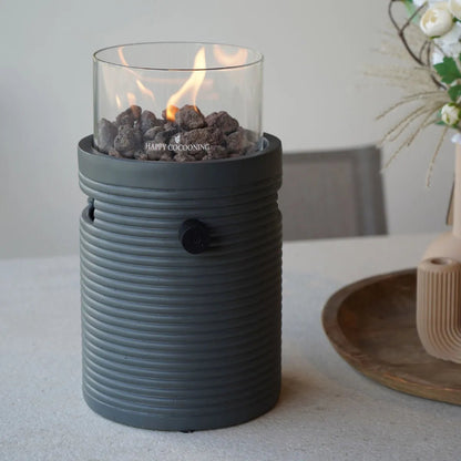 Gray ribbed ceramic fire pit with clear glass top containing glowing lava rocks and flame happy cocooning lumi groove tabletop gas fireplace