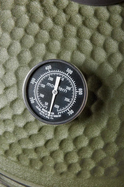 Black circular thermometer with silver casing and white markings branded modern by tef-tru mfg for kamado solo olive green grill