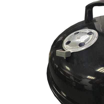Lifestyle 22 inch kettle charcoal BBQ featuring a black glossy enamel-coated cast iron grill with silver vented lid and gray handle